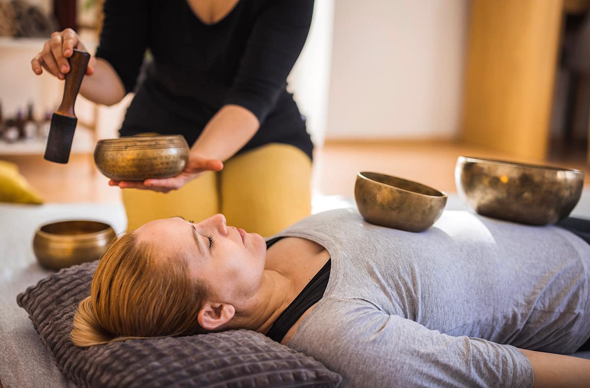 Frequency therapy with Tibetan singing bowls Female healer using Tibetan singing bowls during therapy session